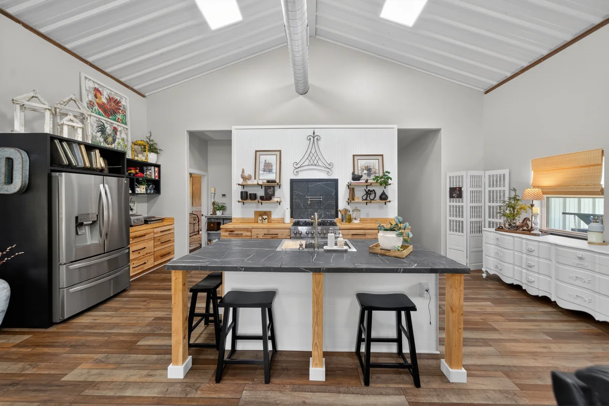 Chef's kitchen with center island, dark marble countertop, Z-Line 6-burner gas range, open shelving, vaulted ceilings, barndominium Chandler TX