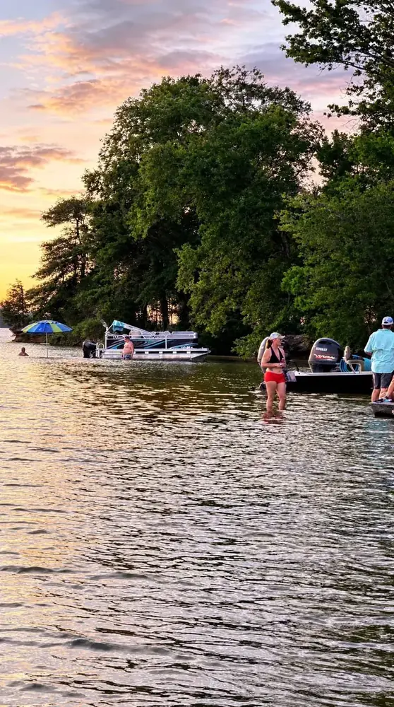 People wading and boating at Reds Island on Lake Palestine Texas at golden hour