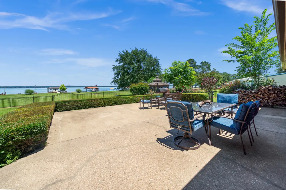 Lakeside patio with outdoor seating overlooking Lake Palestine boathouse and open water at Sunrise Shores Chandler TX