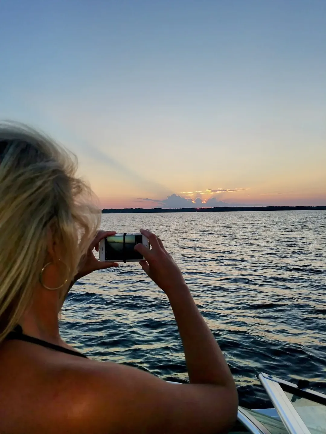 Woman photographing a stunning sunset from a boat on Lake Palestine Texas